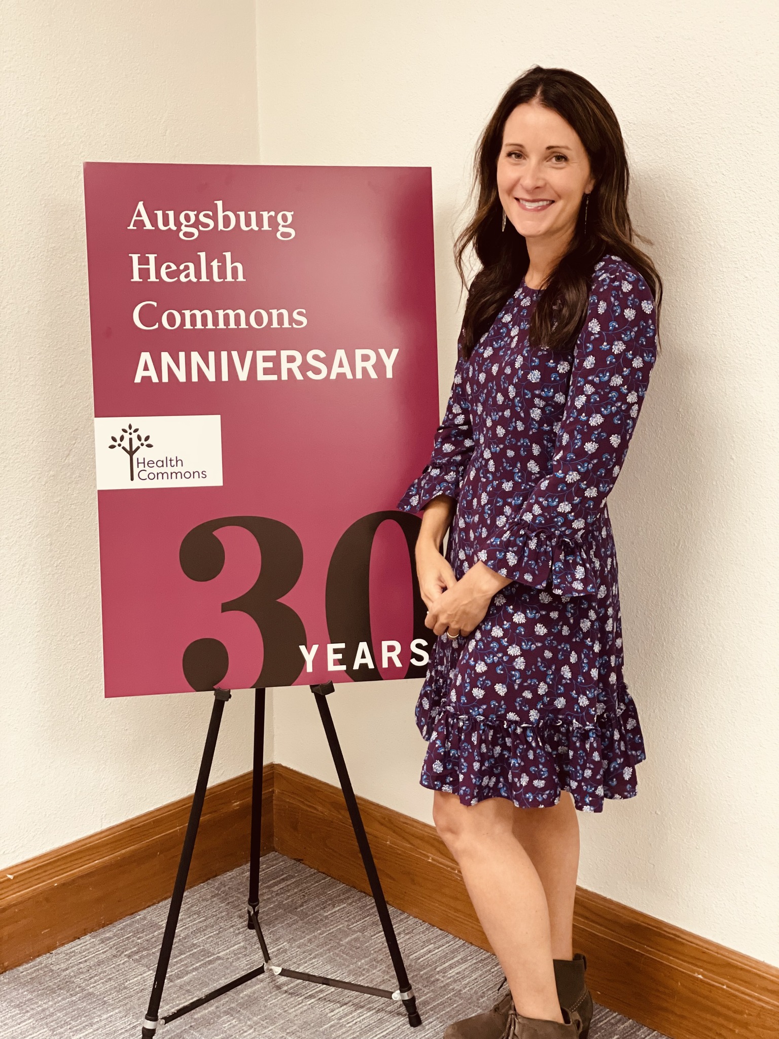 Katie Clark standing by the 30th Anniversary Health Commons sign