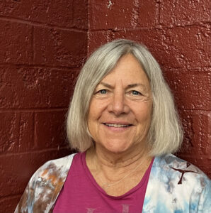 Jan smiling in pink shirt for a headshot.