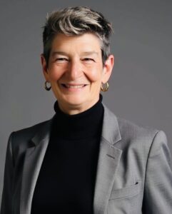 Michele smiling in front of gray backdrop.