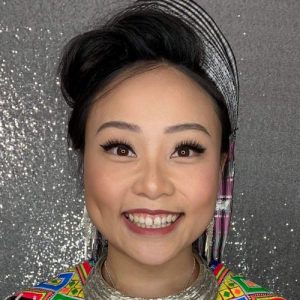 Woman in traditional Hmong dress in front of a silver backdrop