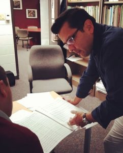 two people in discussion looking at a musical score