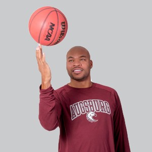 Devean George holding a basketball with the tip of his fingers in a grey background 