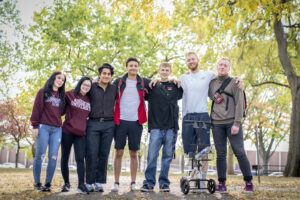 A group of 7 Augsburg StepUP participants stand smiling at the camera with arms linked around each other's shoulders.