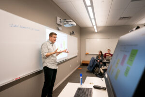 Prof. John Zobitz lectures in front of a whiteboard. His laptop is in the foreground.