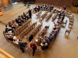 Members of the 1975 Augsburg Choir sing in the Augsburg chapel while sitting in a circle of chairs on May 17, 2025.