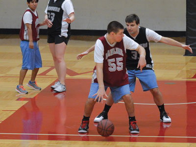 play-1 - Two students playing basketball, while two other students are standing in the back