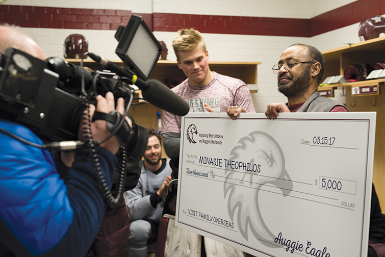 Minasie accepts a check from hockey players