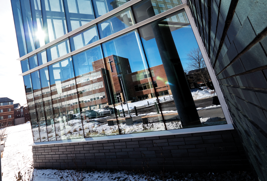 Old Science Hall reflects in the lobby windows of the new Hagfors Center builiding