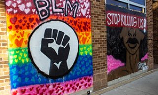 BLM and Lgbtq flag mural along with a Black woman mural next to it with the words "Stop killing us" 