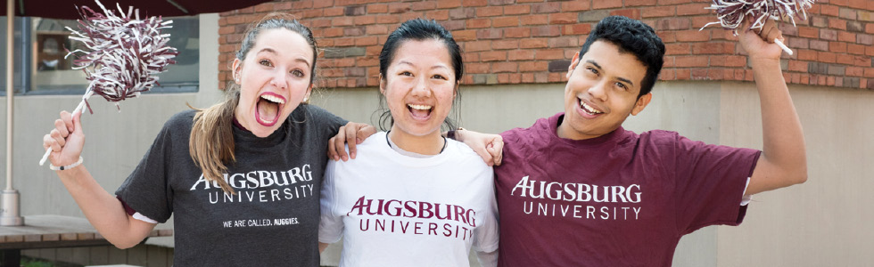 Three students smiling and shaking pom-poms