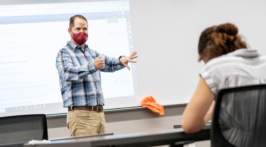 Sociology professor, Tim Pippert teaches in front of a class. He is wearing a face covering for COVID-19 protocal and safety.