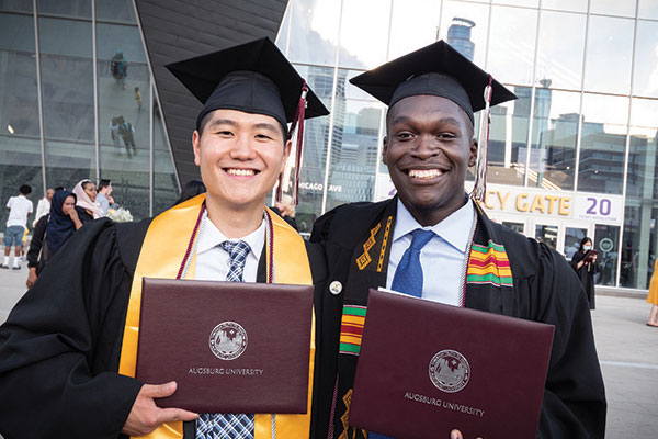 Two students holding their Augsburg University dipolma's outside of US Bank Stadium after the in-person commencement