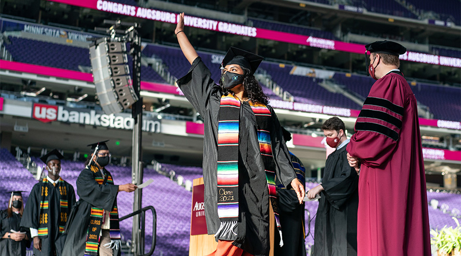 A student walks across the stage during Augsburg's in-person commencement