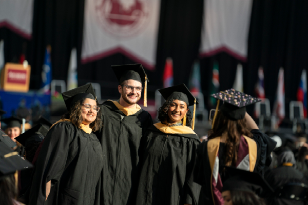 Three students posing for another student taking a photo