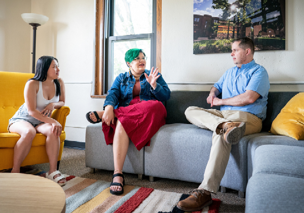 Tim Pippert (right) talks with Augsburg Family Scholars students, Madelyne Yang ’26 (left) and Donovan Holmes ’26 (middle) in the Augsburg Family Scholars lounge on campus.