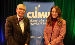 Paul Pribbenow and Katie Clark pose next to a blue banner that reads CUMU: Coalition of Urban and Metropolitan Universities