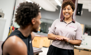 A healthcare professional and a person in athletic attire are smiling in a clinical setting.