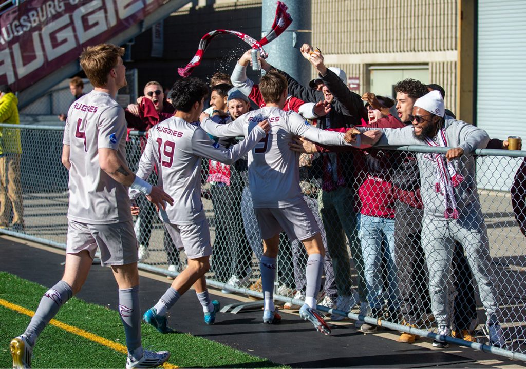 Soccer players celebrating with fans by a fence