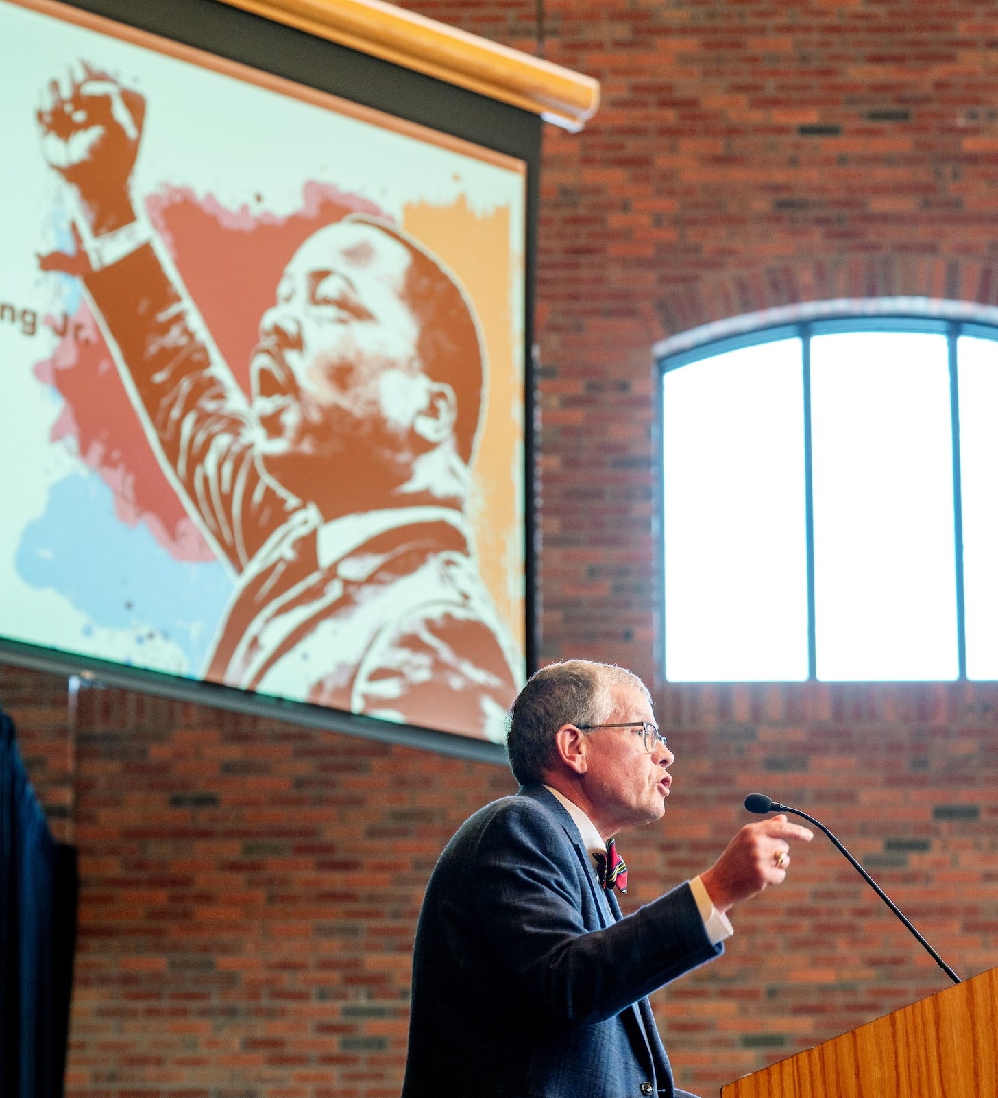 Paul Pribbenow speaks at Augsburg's 39th annual MLK Convocation below an image of Martin Luther King Jr.