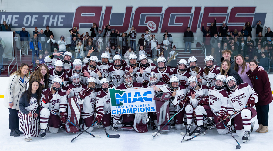 he Augsburg women's hockey team poses on the ice holding a "MIAC Regular Season Champions" banner.