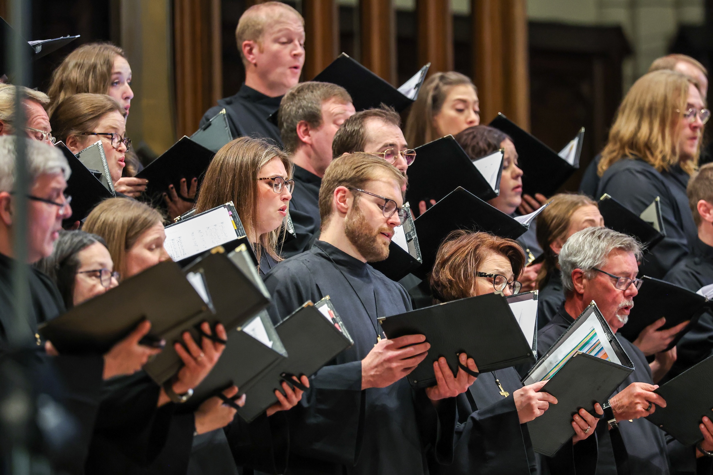 Members of the National Lutheran Choir, dressed in black and holding choir folios, perform in a church setting.