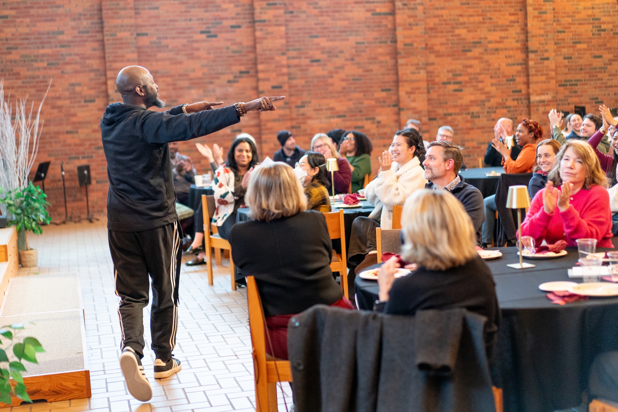 A staff member points to the crowd of colleagues seated at tables in Hoversten Chapel at the 2026 staff awards program.
