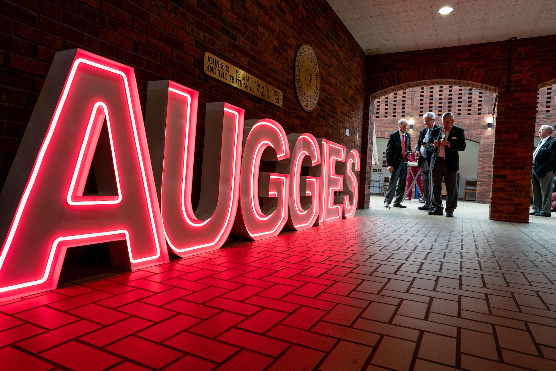 Neon letters spelling "Auggies" in the Hoversten Chapel vestibule