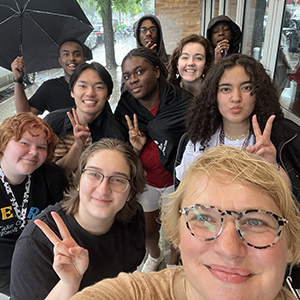 A group of ten people smiling and making peace signs in an outdoor setting.