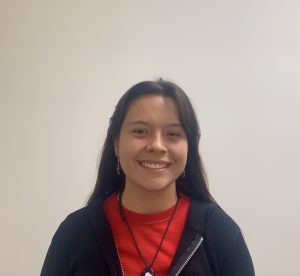 Natalya Arevalo posing for a picture in front of a blank wall.